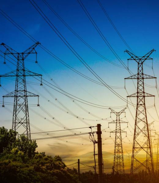 Sun setting behind the silhouette of electricity pylons